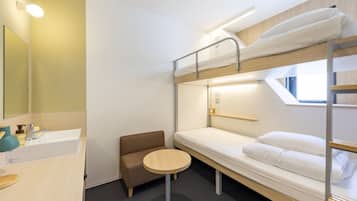 A bunk bed room with a small round table, a sofa, and a sink.