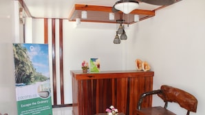 Un espace d’accueil avec un bureau en bois, une chaise, une petite table ornée de fleurs et une affiche faisant la promotion du Cocotel Club.
