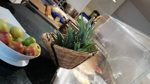 Una encimera de cocina con un bol de manzanas, una planta y una vitrina para alimentos.