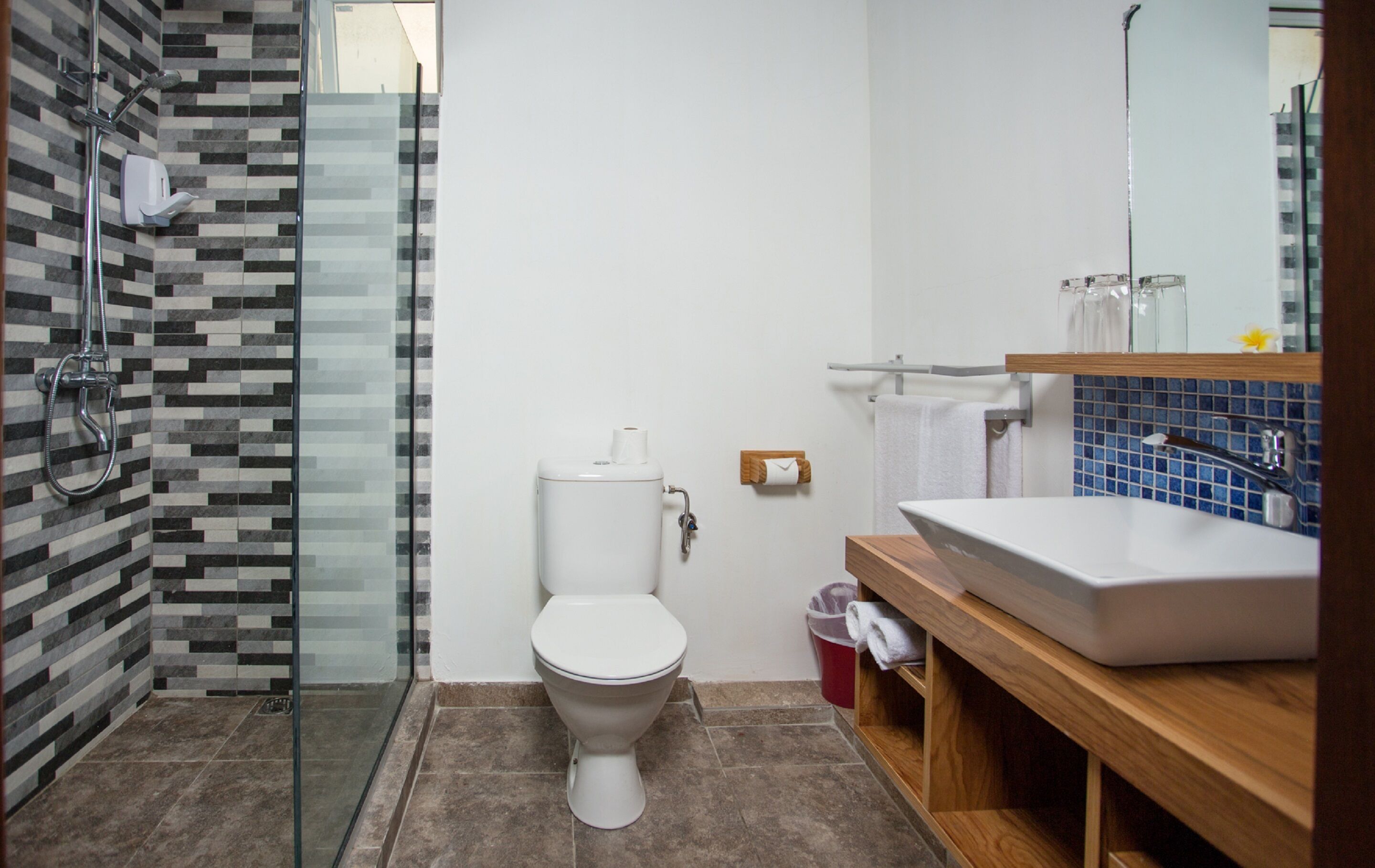 Un baño con inodoro, ducha, lavamanos y espejo.