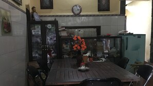 A dining area with a wooden table and chairs, a clock on the wall, and a refrigerator. - Bali Asli Lodge by EPS (Ubud)
