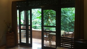 A room with a sliding glass door leading to an outdoor patio area with a table and chairs. - Bali Asli Lodge by EPS (Ubud)