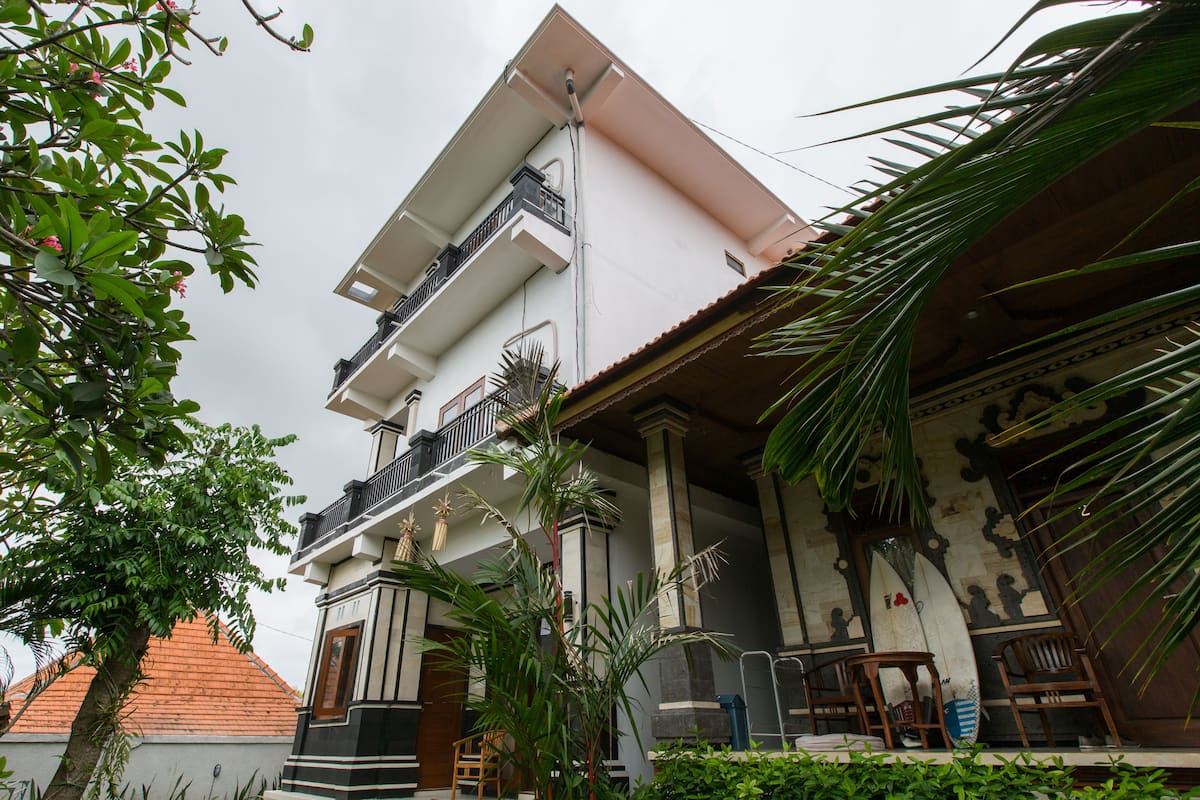 A multi-story building with a balcony, columns, and a tiled roof.