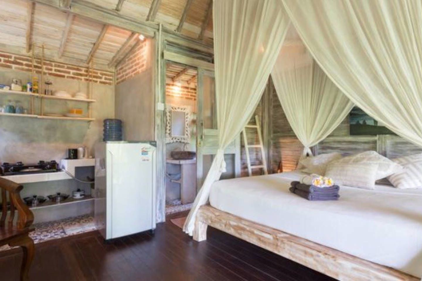 A bedroom with a bed, a small desk, and a refrigerator.