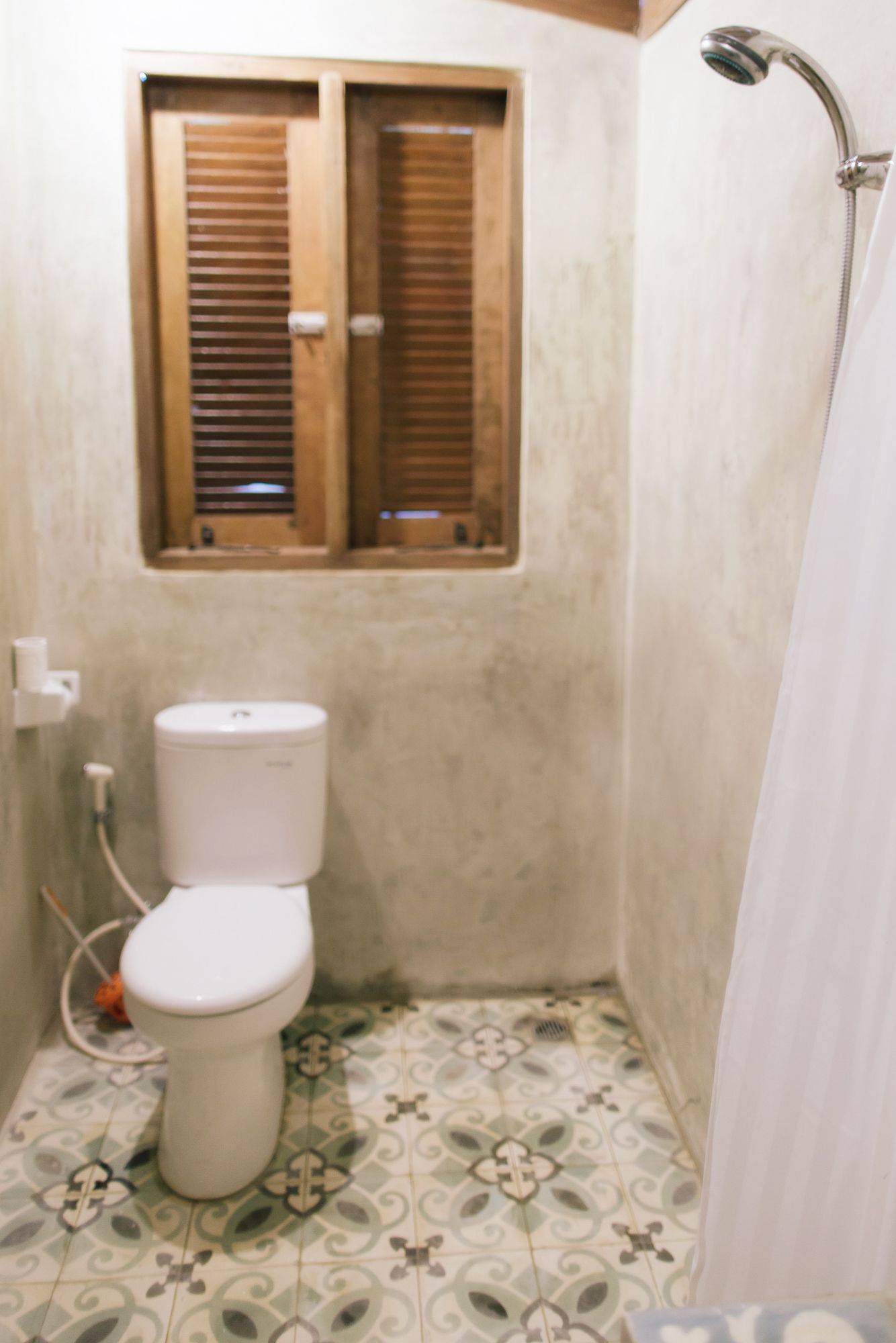 Un bagno piccolo con il water, una finestra con persiane in legno e uno spazio doccia.