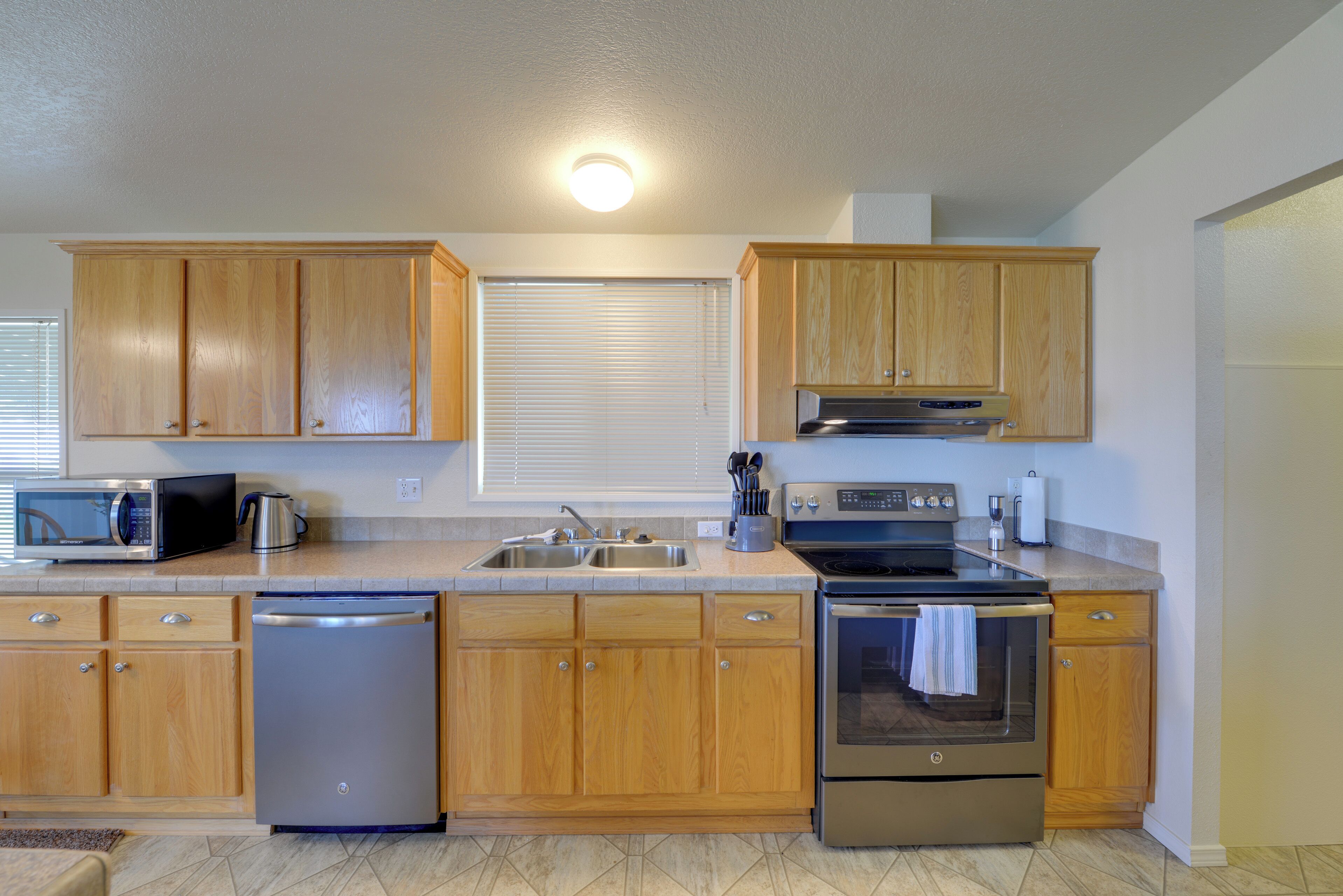 A kitchen with wooden cabinets, stainless steel appliances, a microwave, a dishwasher, a sink, and a stove.