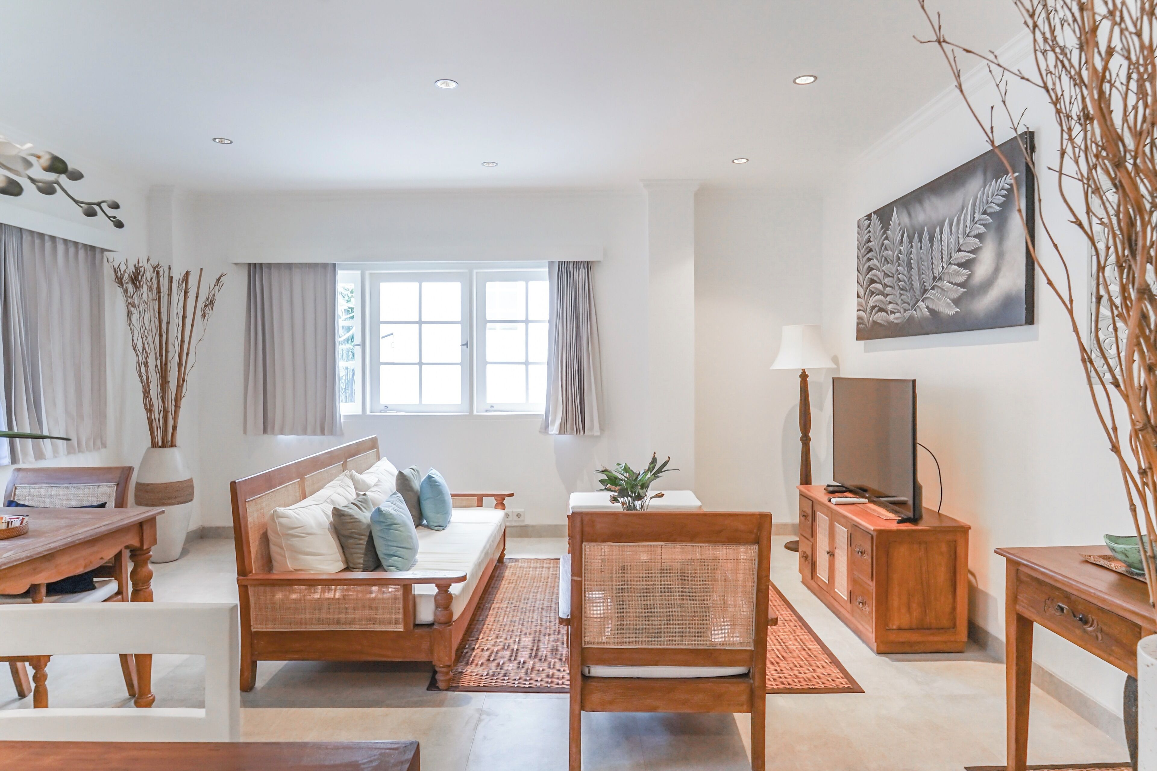 A modern living room with a sofa, a dining table, a TV, and a large window with curtains.