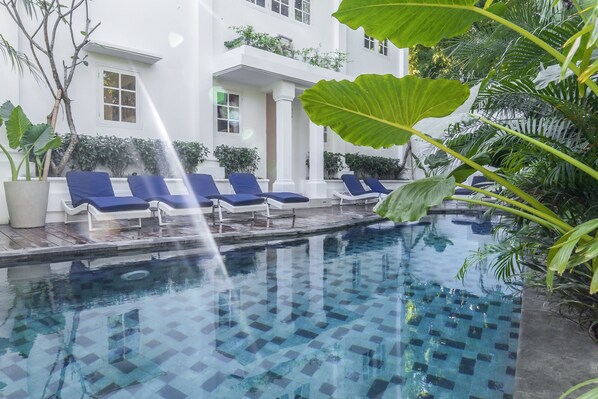 A pool area with blue lounge chairs and a water feature. - Umalas Suite (Kerobokan)