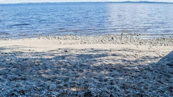 Kallioinen rantaviiva, josta avautuu näkymä merelle ja kaukaiseen maahan.