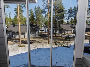 Blick durch ein Fenster auf ein Wohngebiet mit Häusern, Bäumen und schneebedecktem Boden.