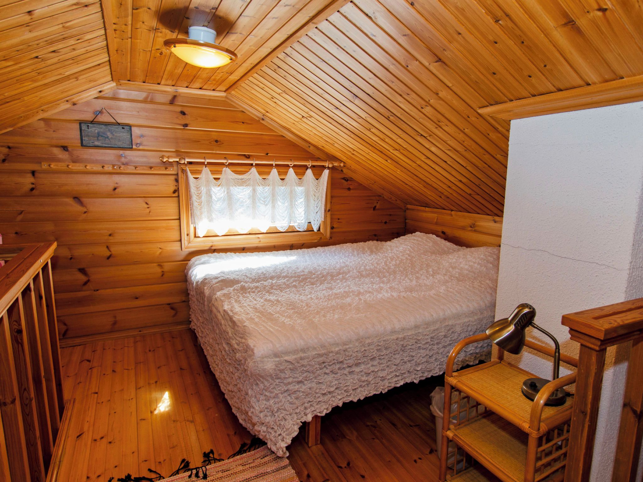 Ein gemütliches Schlafzimmer im Dachgeschoss mit Holzbalkendecke, einem Einzelbett, einem kleinen Tisch und einem Stuhl.