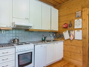A kitchen with white cabinets, a stove, a dishwasher, and a wooden wall.