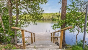 Une jetée en bois qui mène à un lac paisible, entouré d’arbres.