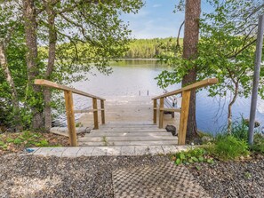 A wooden staircase leading to a dock over a calm lake, surrounded by trees.