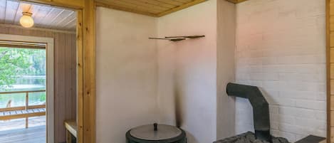 Una habitación con techo de madera, estufa de hierro fundido negra y pared de ladrillo blanco.