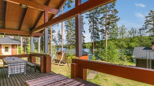 Une terrasse couverte avec vue sur un lac et une forêt.