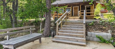 A wooden deck with a bench and a staircase leading to a cabin.