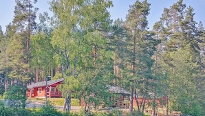 Une cabane entourée d’une forêt dense, avec une jetée qui s’avance sur un lac paisible.
