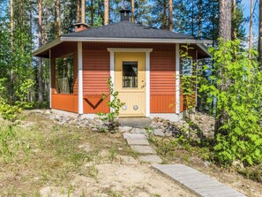 A small cabin with a wooden exterior, a front door, and a chimney.