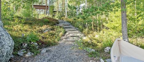 A gravel path leading to a wooden cabin in a forested area.