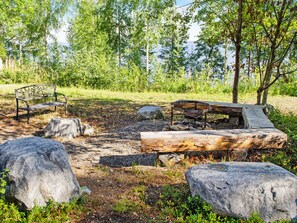 Un camping con un banco de metal, una mesa de picnic de madera y grandes rocas.