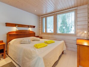 A bedroom with a large bed, two bedside tables, a wooden headboard, and a window with blinds. - Pielislinna/loma-koli by Interhome (Lieksa)