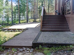 Un escalier en bois mène à un bâtiment doté d’une terrasse et d’un chemin en pierre.