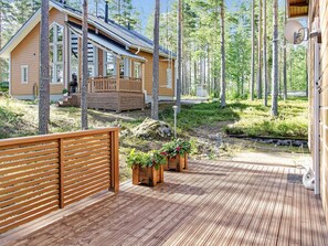 A wooden deck with a view of a cabin surrounded by trees. - Pielislinna/loma-koli by Interhome (Lieksa)