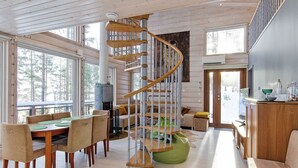 A spacious living area with a wooden staircase, a dining table with chairs, and a cozy seating area with a green bean bag. - Pielislinna/loma-koli by Interhome (Lieksa)