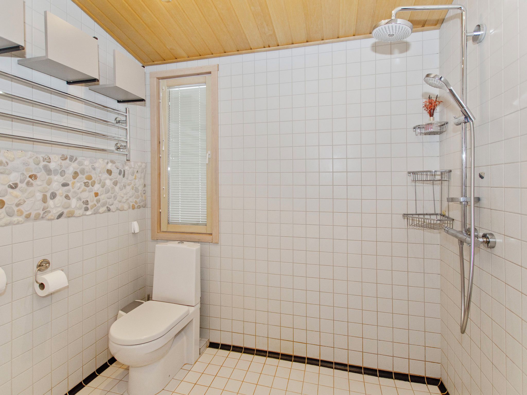 A small bathroom with a toilet, a shower, and a window.