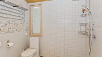 A small bathroom with a toilet, a shower, and a window.