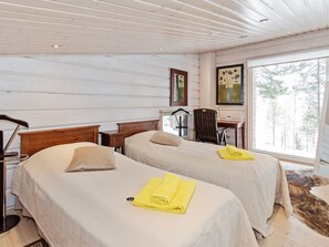 A hotel room with two beds, a desk, and a chair. - Pielislinna/loma-koli by Interhome (Lieksa)