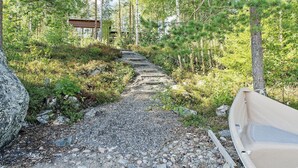 A gravel path leading through a forested area with a wooden structure in the background. - Pielislinna/loma-koli by Interhome (Lieksa)