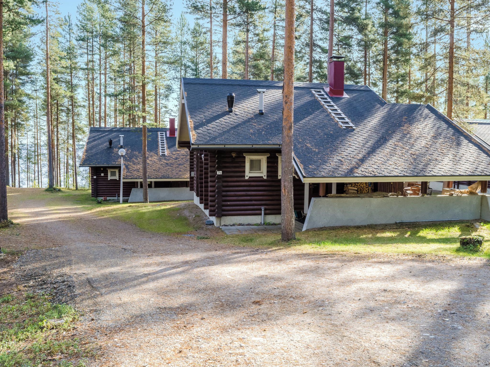 Mökki, jossa on kalteva katto, savupiippu ja pieni kuisti.