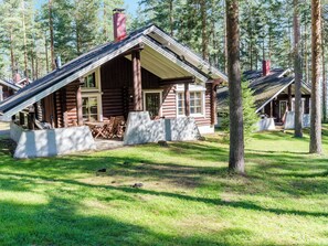 Een vakantiehuisje van hout met een veranda, buitenzitplaatsen en een helder uitzicht op het omliggende bos.