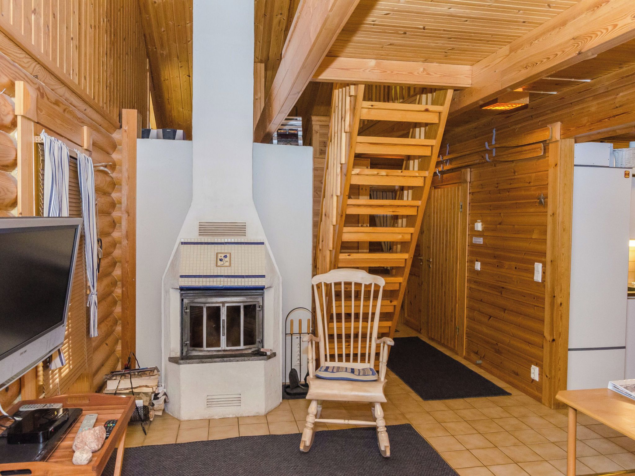Ein Blockhaus-Interieur mit Kamin, einer Holztreppe und einem Fernseher.