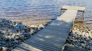 Un muelle de madera que se adentra en aguas tranquilas con una costa rocosa.