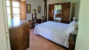 Una camera da letto con soffitto in legno, un letto con copripiumino bianco, un comò e uno specchio.