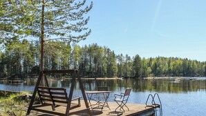 A wooden dock extending into a calm lake, surrounded by dense forest.