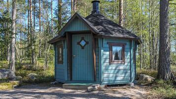 A small cabin with a pitched roof, a chimney, and a door with a diamond-shaped window.