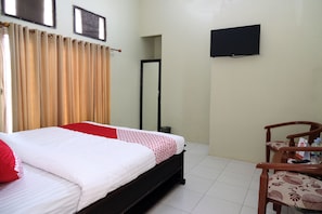 A hotel room with a bed, a chair, a television, and a door.
