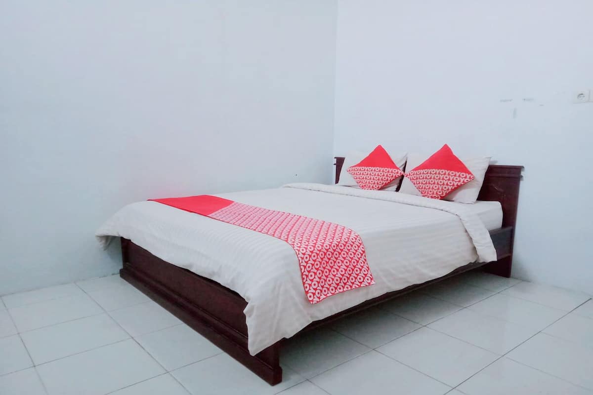 A neatly made bed with a white and red bedspread, two matching pillows, and a wooden headboard.