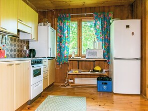 Cocina compacta con armarios de madera, estufa, microondas y refrigerador.