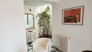 A room with a white chair, a white table, a radiator, a mirror, a dresser, and a plant. - Village house, sea view, Cerbère (Cerbère)