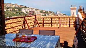 A terrace with a table set for two, overlooking a coastal town with buildings and a lighthouse. - Village house, sea view, Cerbère (Cerbère)