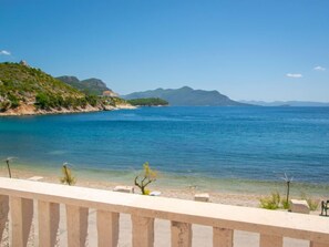 Une vue sur la côte, avec une mer bleue et limpide, une plage de sable et un paysage montagneux en arrière-plan.