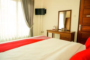 A hotel room with a bed, a wooden desk, a flat-screen TV mounted on the wall, and a door. - OYO 733 Mina Homestay (Bukittinggi)
