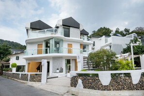 Une maison moderne à deux étages, dotée d’un balcon, d’un mur en pierre et d’une porte en bois.