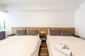 A hotel room with two beds, wooden headboards, and a nightstand with a lamp. - JK Maritime Luxury Suite (George Town)