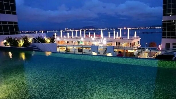 Ein modernes Hotel mit Poolbereich, Blick auf das Wasser und einer gut beleuchteten Fassade.